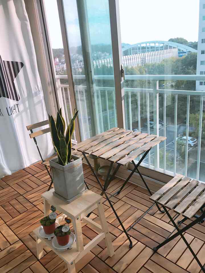 明るい自然光と植物がある木目調の床と家具のある雰囲気のあるベランダカフェスペース