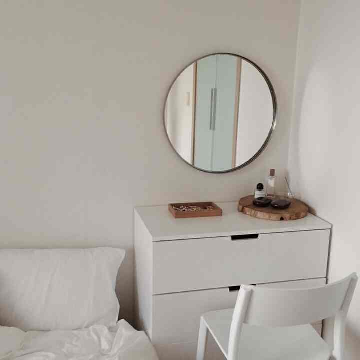 White-toned bedroom featuring a dresser used as a vanity with a simple and tidy atmosphere