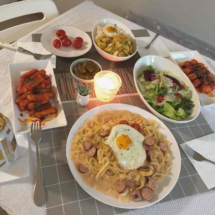 落ち着いたグレーのトーンのダイニング、様々な料理と小さな植物、キャンドルが配置された雰囲気のあるインテリア