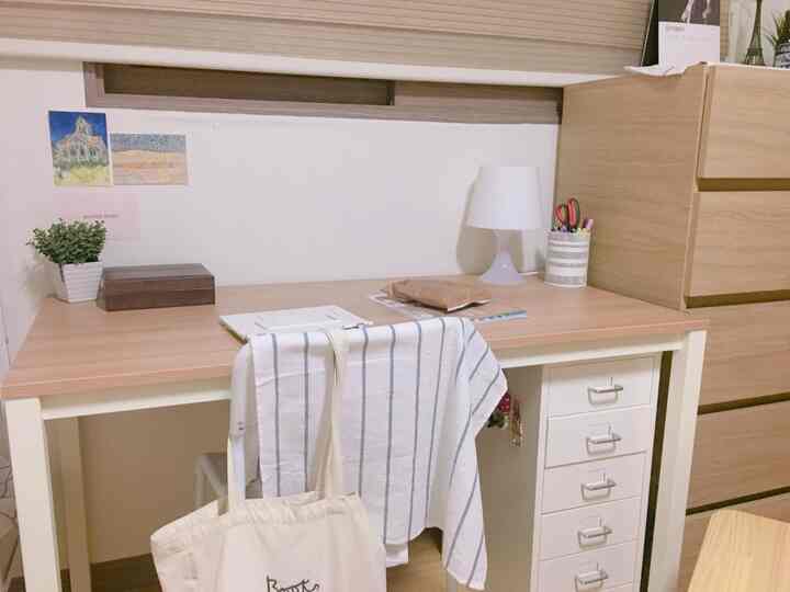 Natural wood tone and white studio bedroom desk featuring a neat drawer unit and table lamp in a cozy atmosphere