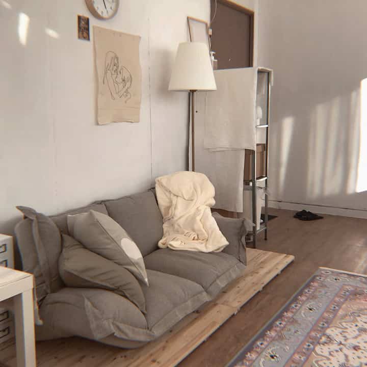 Beige and wood-toned natural 6-tatami-sized home office workspace featuring a gray sofa and Persian rug