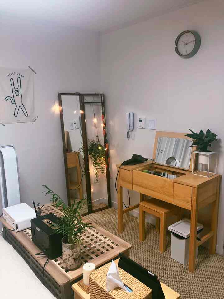 Cozy bedroom with natural wood tones and beige rug featuring a vanity and full-length mirror