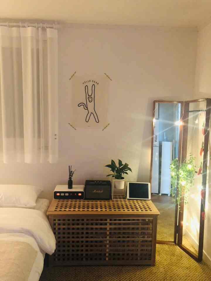 Bedroom with white and wood tones, featuring a large standing mirror and plants in a cozy natural light setting