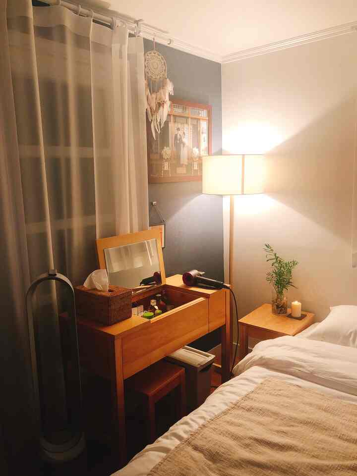 A cozy bedroom with soft beige and white tones featuring a wooden vanity and mood lighting creating a warm atmosphere