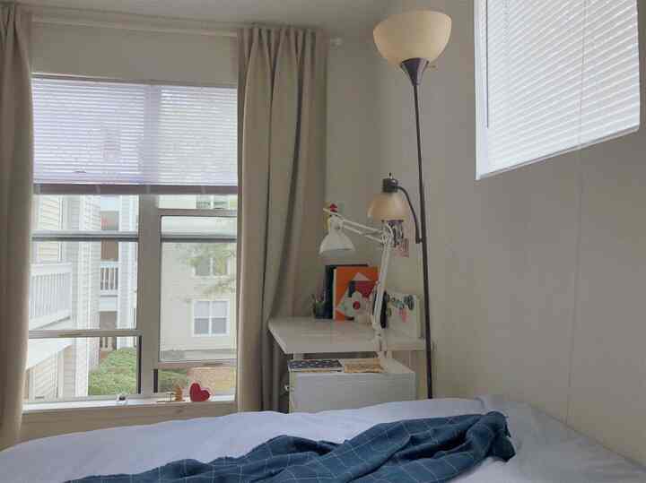 ベージュとホワイトのトーンのコンパクトな寝室、中央にベッド、右側にデスクが配置された雰囲気のある空間