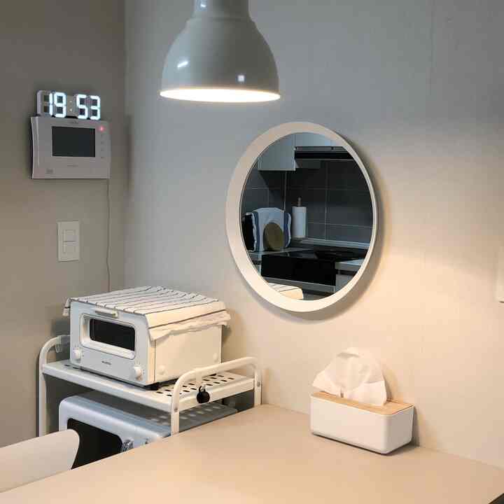 White-toned kitchen and dining area featuring a round mirror and pendant light in a clean, simple interior