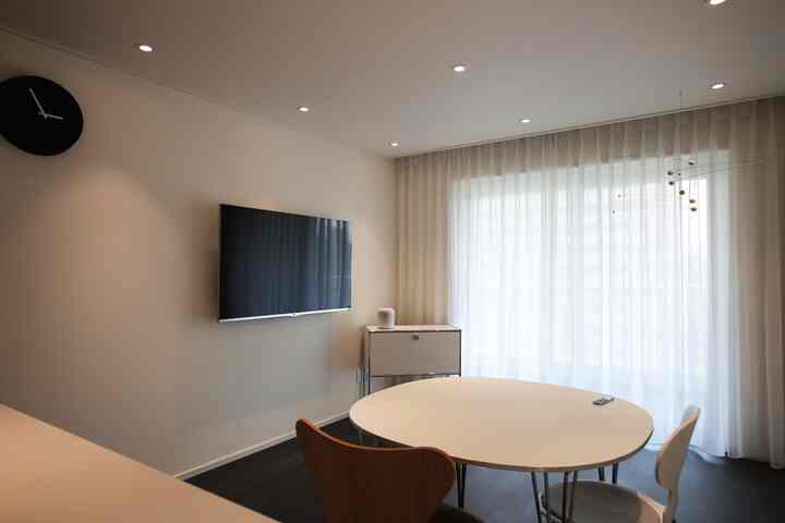 白を基調としたミニマルなリビング、円形のダイニングテーブルと椅子が配置された落ち着いた空間