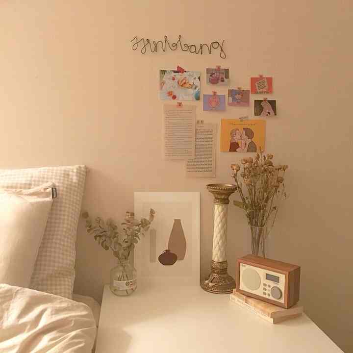 Beige-toned bedroom featuring bed pillows and natural plants on a clean and cute nightstand setup
