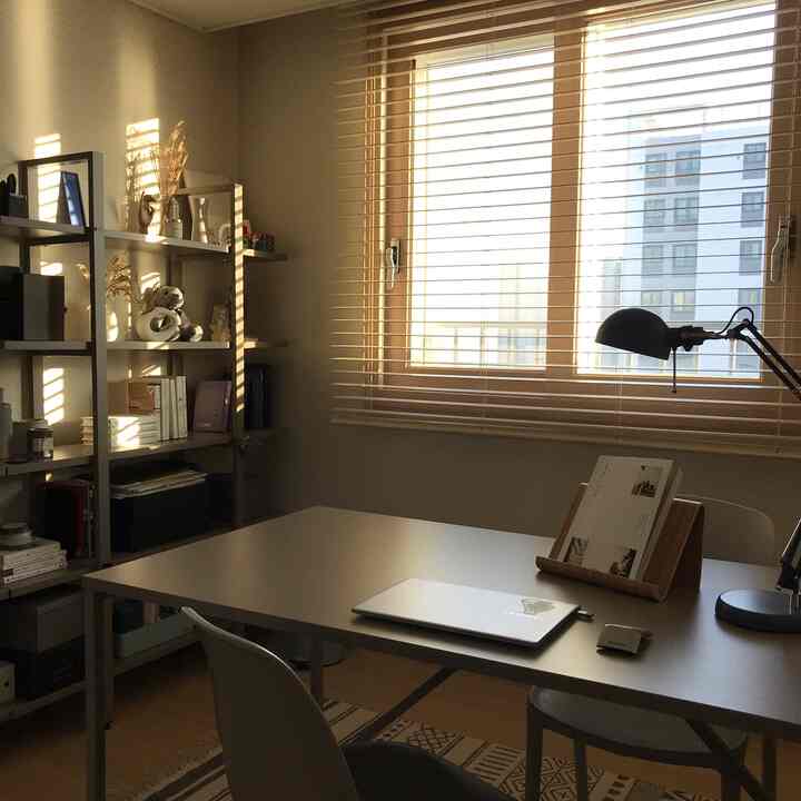 Natural warm-toned home office space featuring central desk and left bookshelf with calm atmosphere