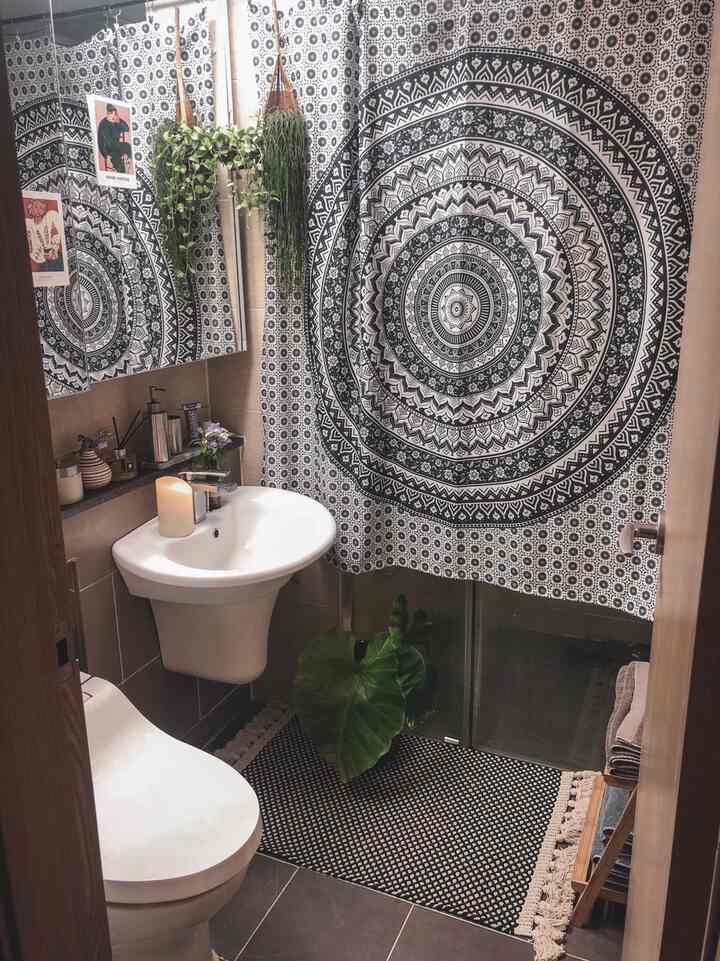 自然の雰囲気を感じるバスルーム、模様のカーテンと緑の植物が配置されたモダンな空間