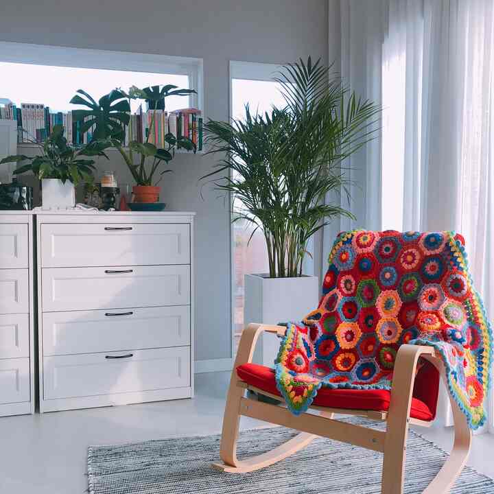 White walls and dresser, plants, and a colorful throw blanket in a natural-toned living room space