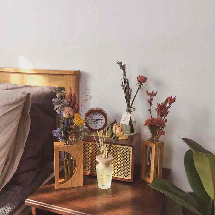 温かみのある木目調とドライフラワーが配置された居心地の良い寝室のナイトテーブル