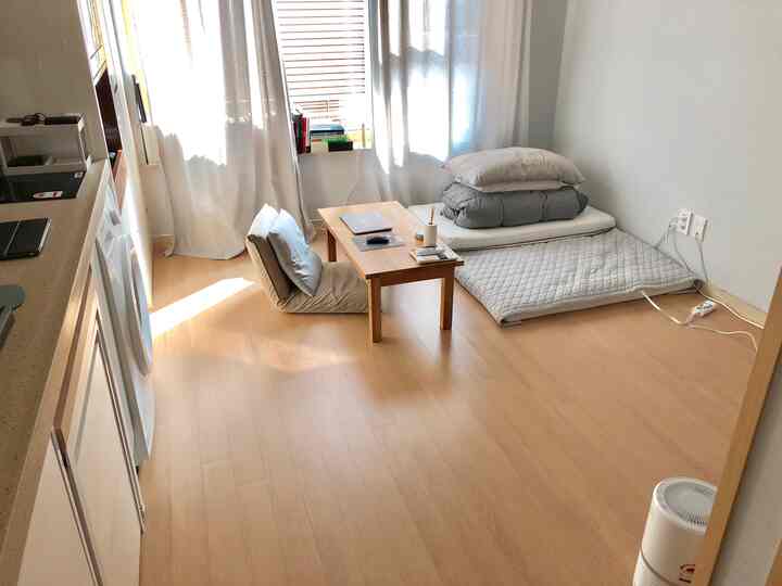 ナチュラルな色調の5坪ワンルーム。床生活用の座椅子、折りたたみ布団、小さな木製テーブルが配置されたシンプルでミニマルな空間