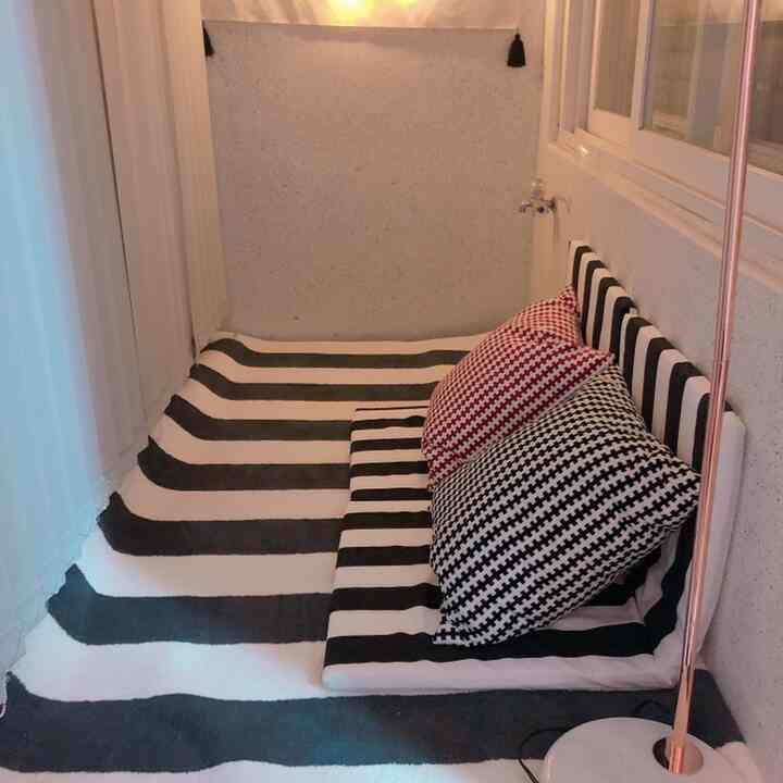 Cozy floor seating area with black-and-white striped carpet and cushions by a window, featuring a floor lamp creating a warm atmosphere