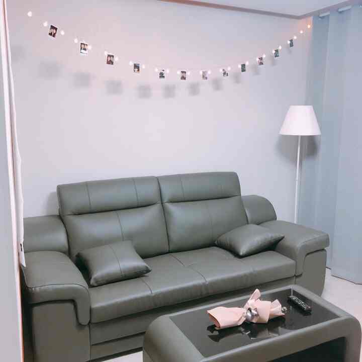 ブラウン調のリビング、3人掛けソファと同色のテーブル、ストリングライトとポラロイド写真が配された印象的な空間