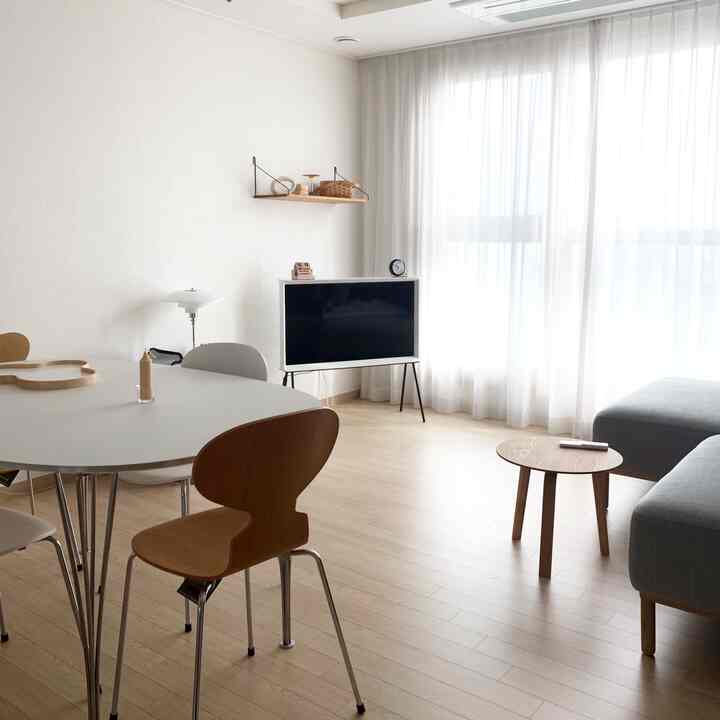 A white and wood tone living room featuring a dining table and sofa in a natural modern style