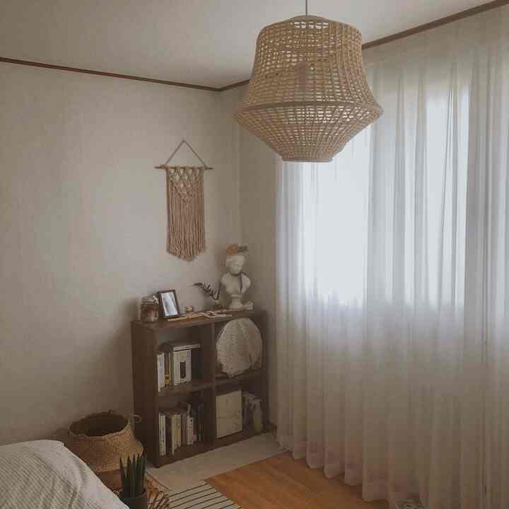 Beige and white toned bedroom featuring natural material lighting and bookshelf with a cozy, vintage atmosphere
