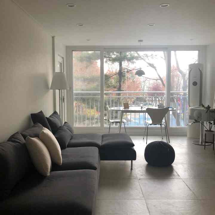 ホワイトとブラックの色調のリビング、広い窓とソファ、ダイニングテーブルが配置されたシンプルで自然な雰囲気のインテリア