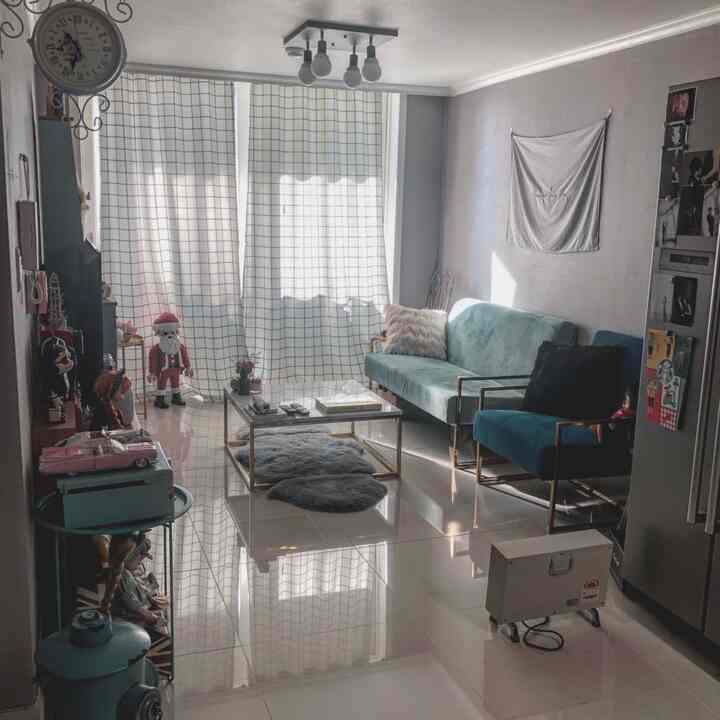 White and blue toned living room featuring a blue velvet sofa and transparent glass coffee table in a neat newlywed home interior