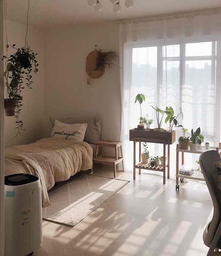 Beige and wood-toned bedroom featuring indoor plants and stools, creating a quiet and natural ambiance with soft sunlight