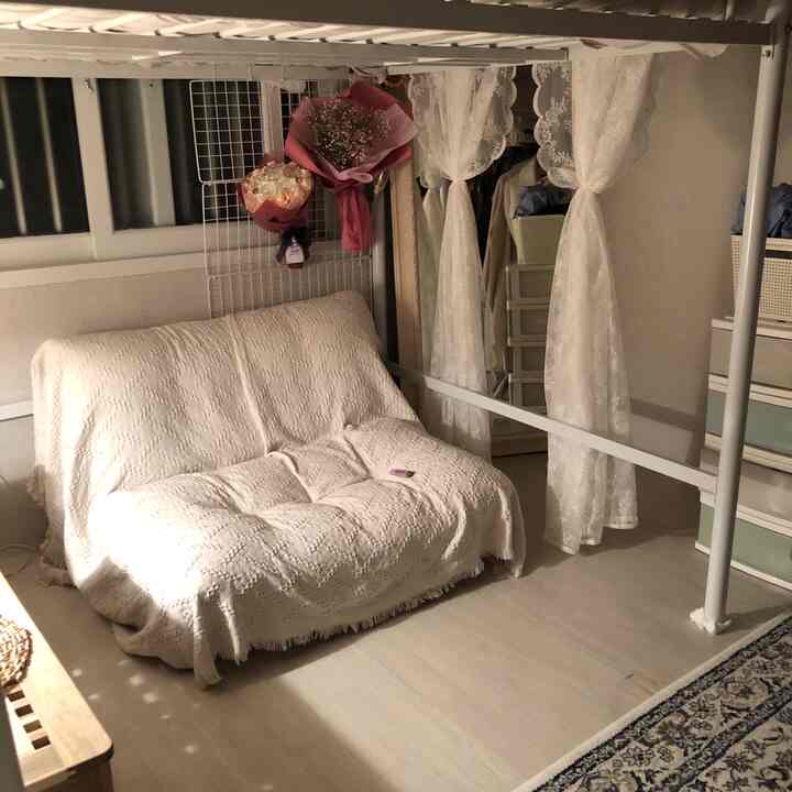 Natural-toned cozy bedroom featuring a sofa bed and lace curtains creating a comfortable ambiance
