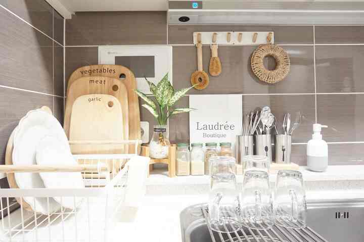 Natural-toned kitchen featuring wooden cutting boards, cutlery, and a small plant on clean white countertop