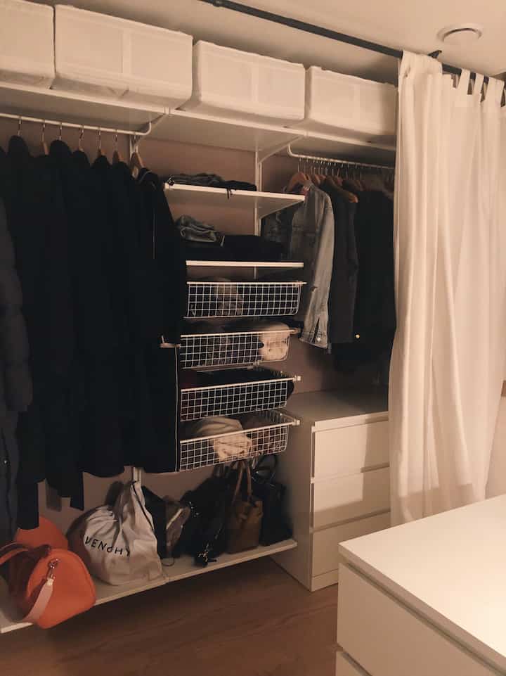 White and natural tone walk-in closet featuring organized clothes and dresser in a clean space
