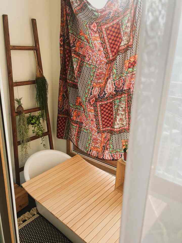 Warm wood tone veranda featuring natural plants and patterned linen curtain creating a cozy atmosphere