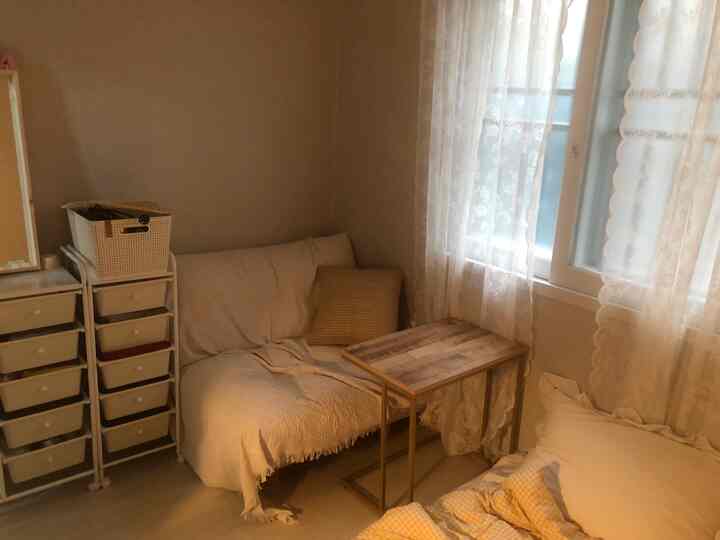 Wood tone and beige small 1.5-pyeong studio apartment featuring a white sofa and lace curtains with a natural atmosphere