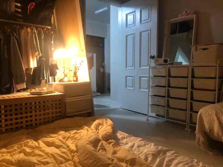 Warm beige toned studio bedroom featuring a bed and storage drawers with a cozy atmosphere