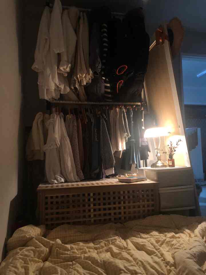 A cozy studio apartment in warm ivory and wood tones, featuring a hidden hanger behind a large mirror for neat storage and a comfy ambiance