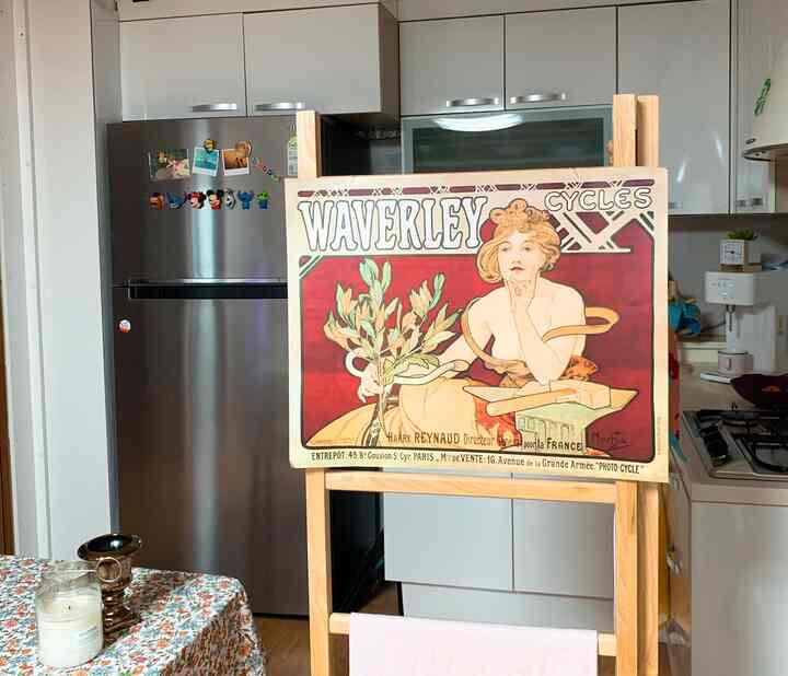 Warm wood-toned kitchen and dining area featuring a retro poster on a wooden room divider partially concealing the restroom, creating a cozy interior