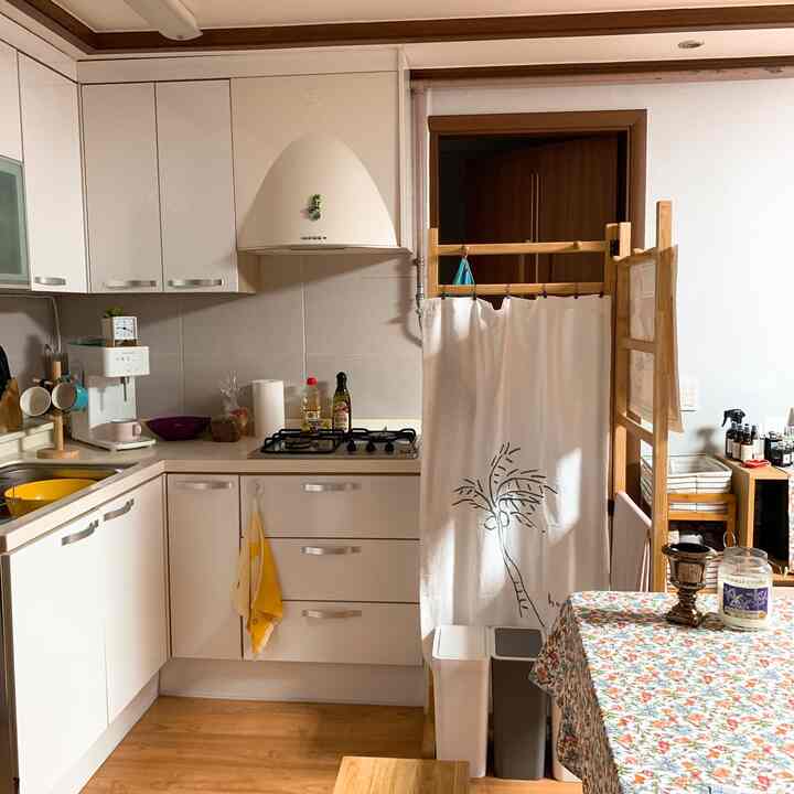 ホワイトとウッドトーンが調和したキッチン空間、レトロな花柄のテーブルクロスが配置された雰囲気のあるキッチン