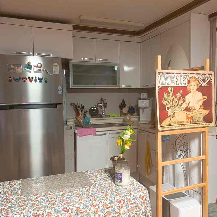 White tone kitchen featuring floral tablecloth on dining table and stainless steel refrigerator creating a cozy atmosphere