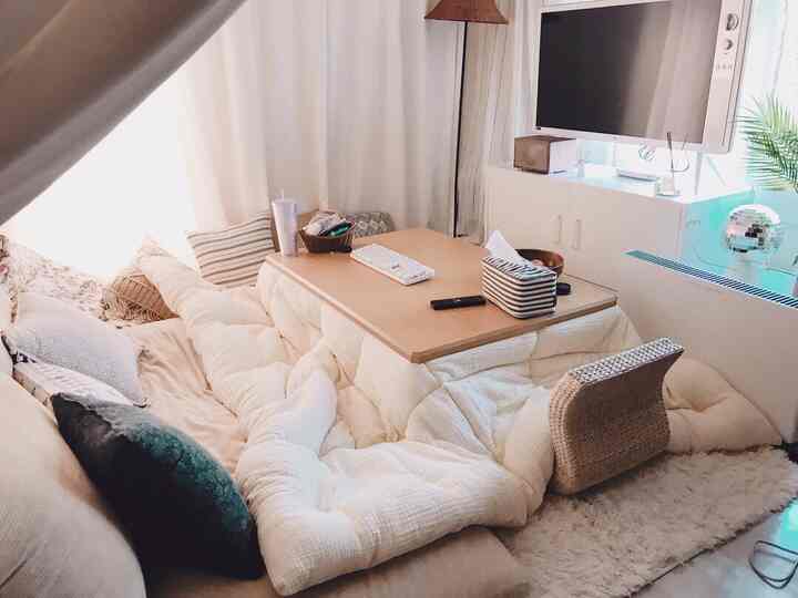 Natural tone living room featuring a central kotatsu and corduroy floor cushions, creating a cozy winter space