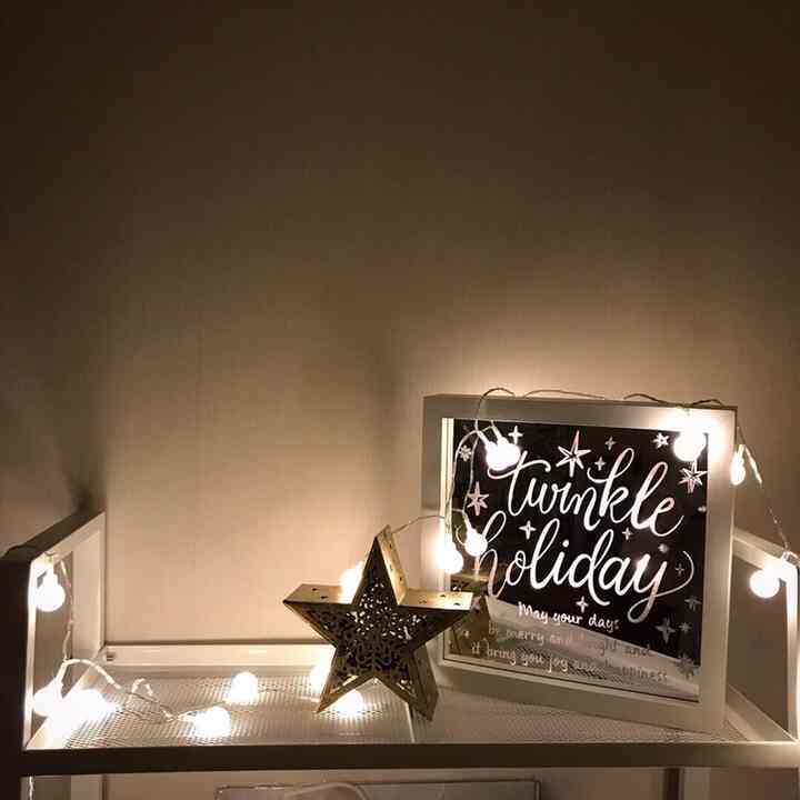 Simple shelf with white warm lighting featuring a picture frame and star ornament in a natural tone setting
