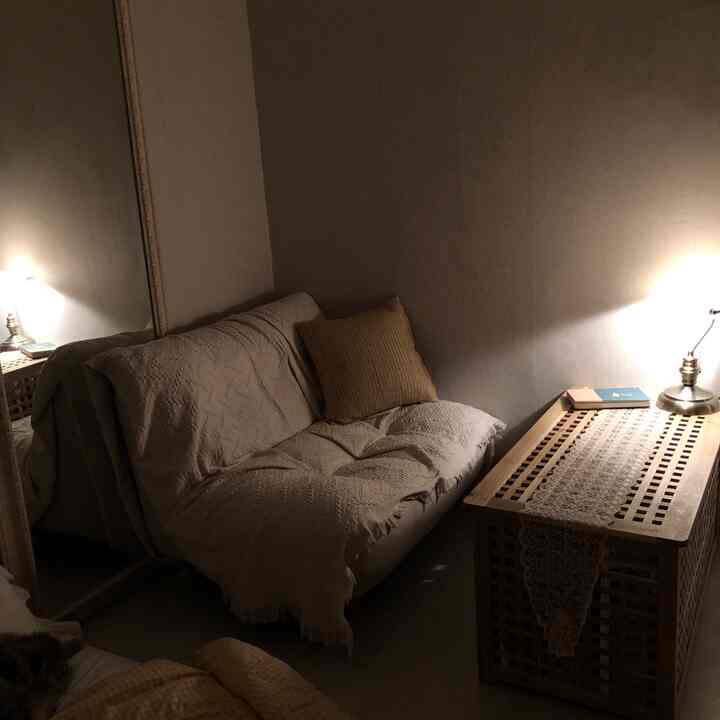 Warm beige and natural wood tone studio apartment living room featuring a cozy sofa and a table with a runner, illuminated by soft lighting