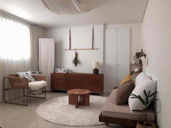 白いカーテンとブラウンの木目調家具が配置された雰囲気のあるリビングルーム