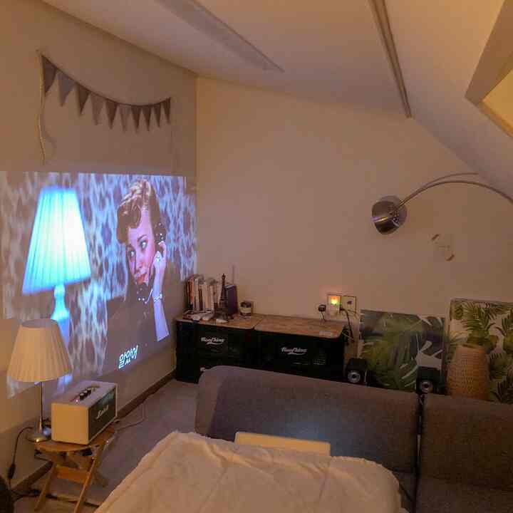 Gray-toned loft room featuring a gray sofa and a projector creating a cozy home cinema atmosphere