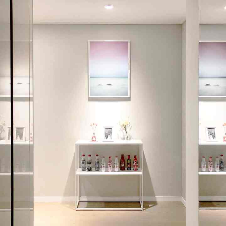 白とナチュラルトーンの玄関、中央に白いコンソールテーブルと額縁が配置されたシンプルで清潔感のあるインテリア