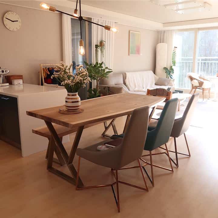 Beige and wood tone living and dining room featuring dining table, chairs, and multiple plants creating a natural atmosphere