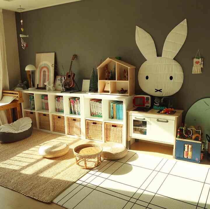 Natural-tone kids' room featuring bookshelves, storage baskets, toys, and a large rug with bright, cozy atmosphere