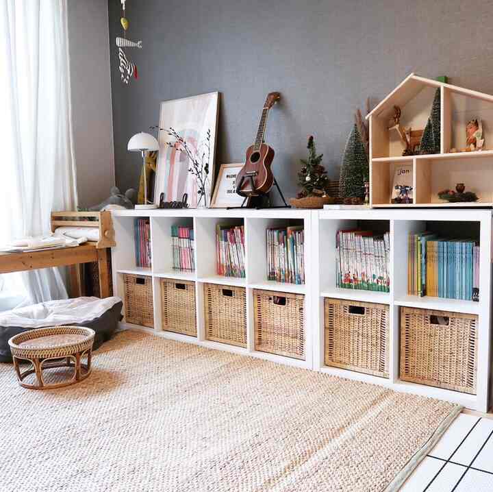 ナチュラルな色調の子供部屋、白い本棚とバスケット、子供の本やおもちゃが整頓された快適なインテリア