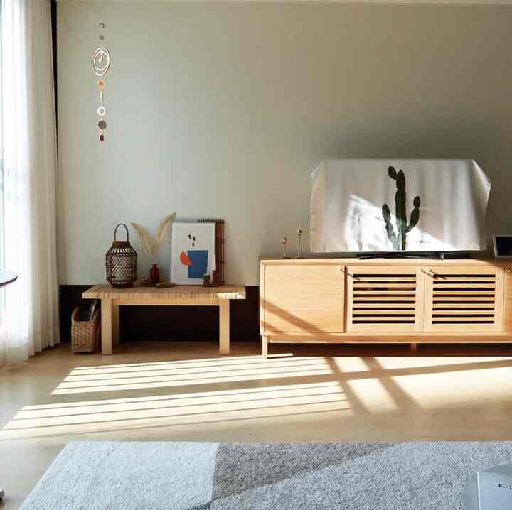 Warm wood-tone living room featuring a TV stand and rattan candle holder in a cozy cafe-style setting
