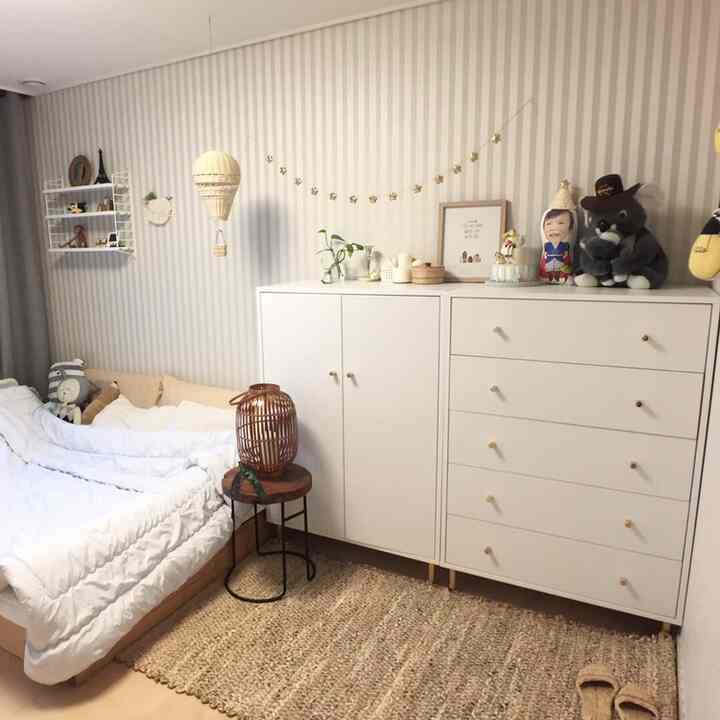 白とベージュのトーンが調和した子供部屋、ベッドとドレッサーが配置され、落ち着いた自然な雰囲気のインテリア