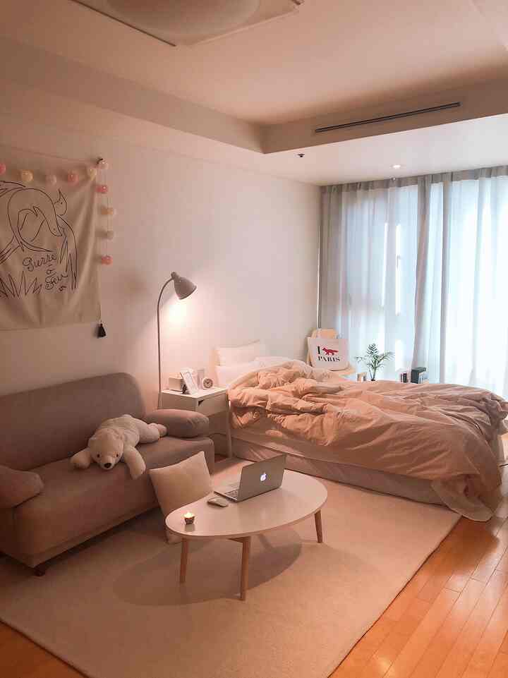 白とベージュの木目調が調和するワンルームの寝室兼リビングスペース、シンプルで自然な雰囲気のインテリア