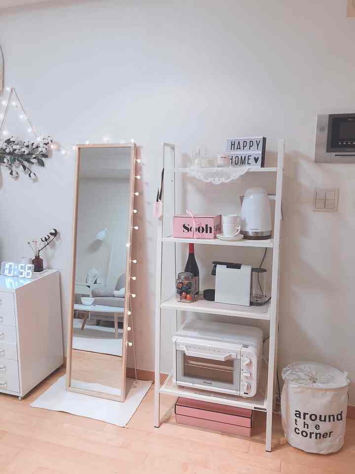 ホワイトトーンのワンルームキッチンスペース、ラックにはミニオーブンやコーヒーマシンが整然と並び、落ち着いたおうちカフェの雰囲気