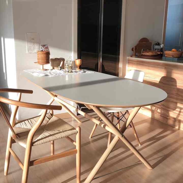 温かな木目調と白いダイニングテーブルが配置された、日差しが差し込む自然な雰囲気のキッチン兼ダイニングスペース