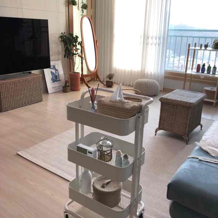 Bright white wood tone living room featuring a 3-tier trolley and rattan storage with cozy atmosphere