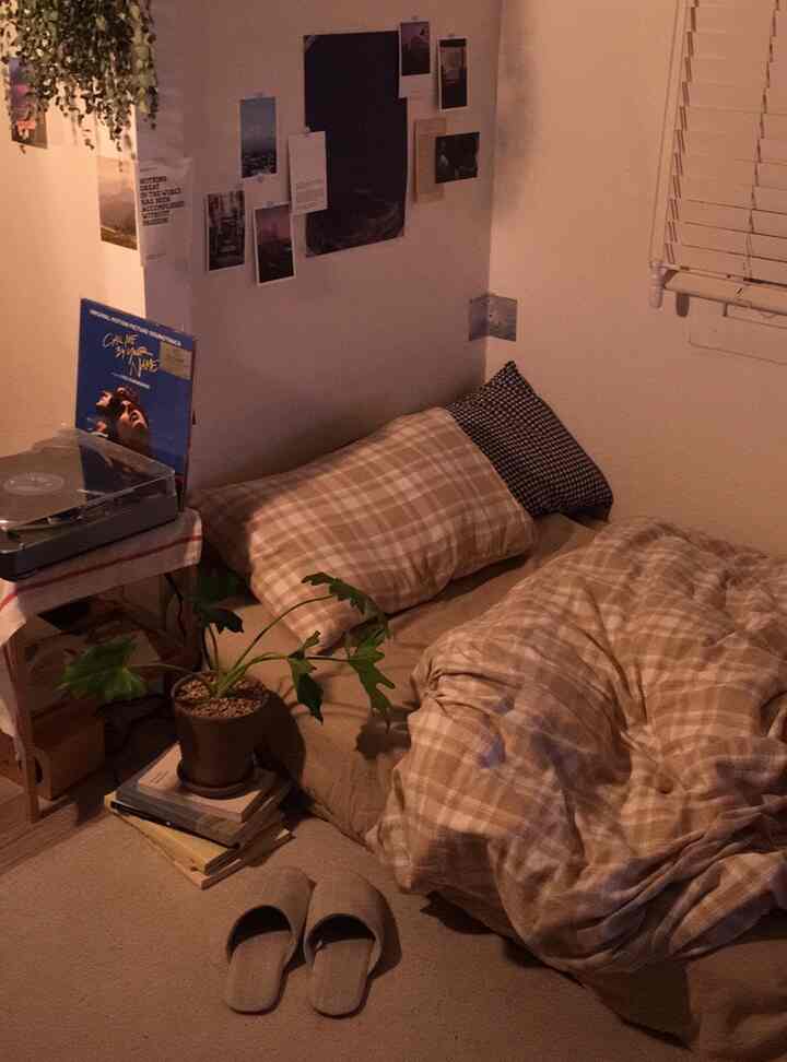 温かみのあるベージュ色調のコンパクトなワンルーム寝室、床ベッドとヴィンテージレコードプレーヤーが印象的な空間を演出